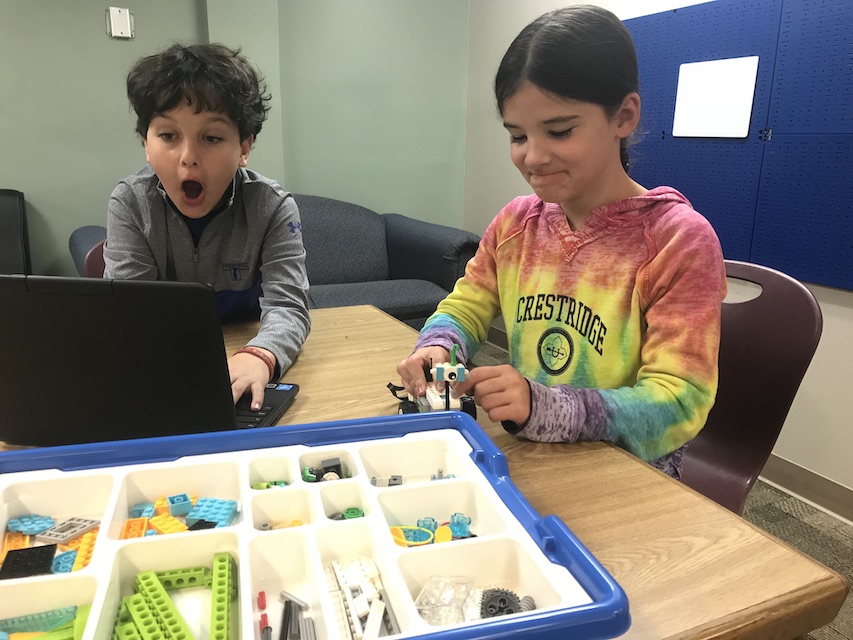 Two children build a programmable LEGO robot.