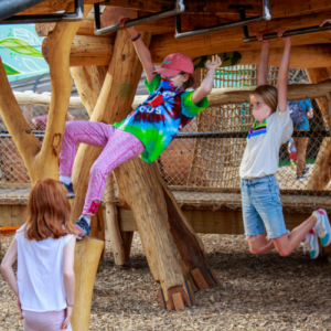 Two children swings on wooden monkey bars.