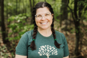 Brunette woman with braided pigtails wearing a green t-shirt