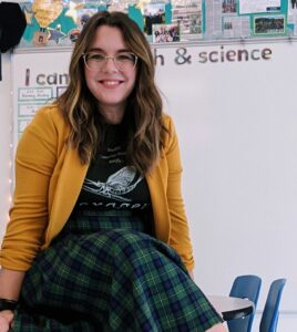 Photo of woman with long wavy brown hair in yellow cardigan with black t-shirt