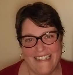 Woman with short brown hair and dark-rimmed glasses wearing a red shirt